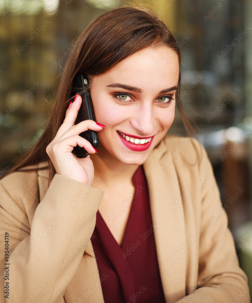 Nice girl in coat uses mobile phone in summer cafe Nice girl in coat uses mobile phone in summer cafe