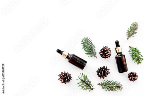 Pine essential oil in bottles on white background top view copy space. Pattern with pine branch and cone