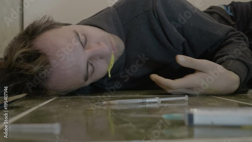 Intoxicated young boy lying on the bathroom floor spasm unconsciously and vomiting after injecting an overdose of heroin drug