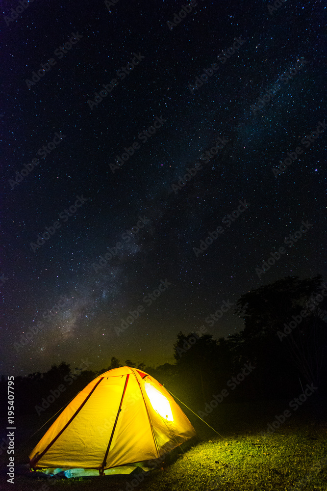 Orange tent glows under night sky.