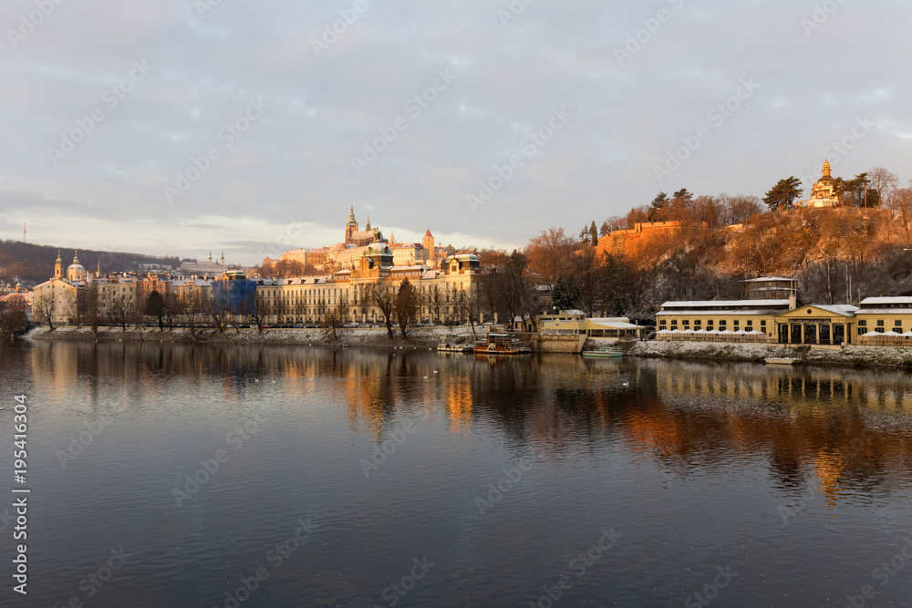 Sunny snowy early morning Prague Lesser Town with gothic Castle above River Vltava, Czech republic