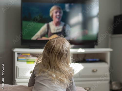 Little girl watchin a movie on TV at home photo