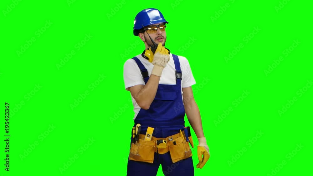 Builder speaks in a walkie talkie to the colleagues. Green screen Builder speaks in a walkie talkie to the colleagues. Green screen