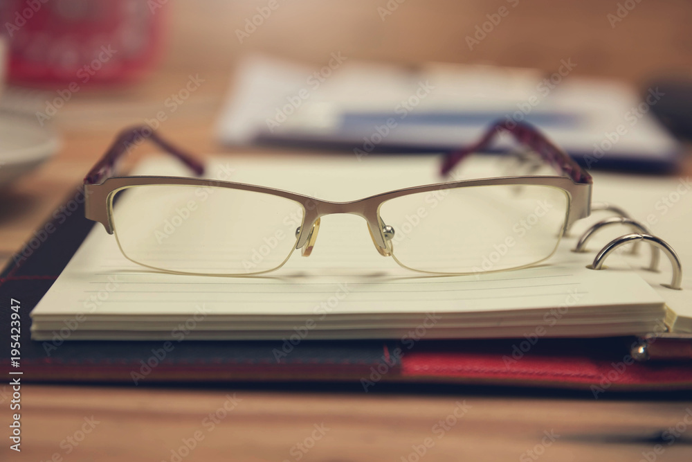 Business and finance concept of office working, Closeup eyeglasses on office desk in working day. Business and finance concept of office working, Closeup eyeglasses on office desk in working day.