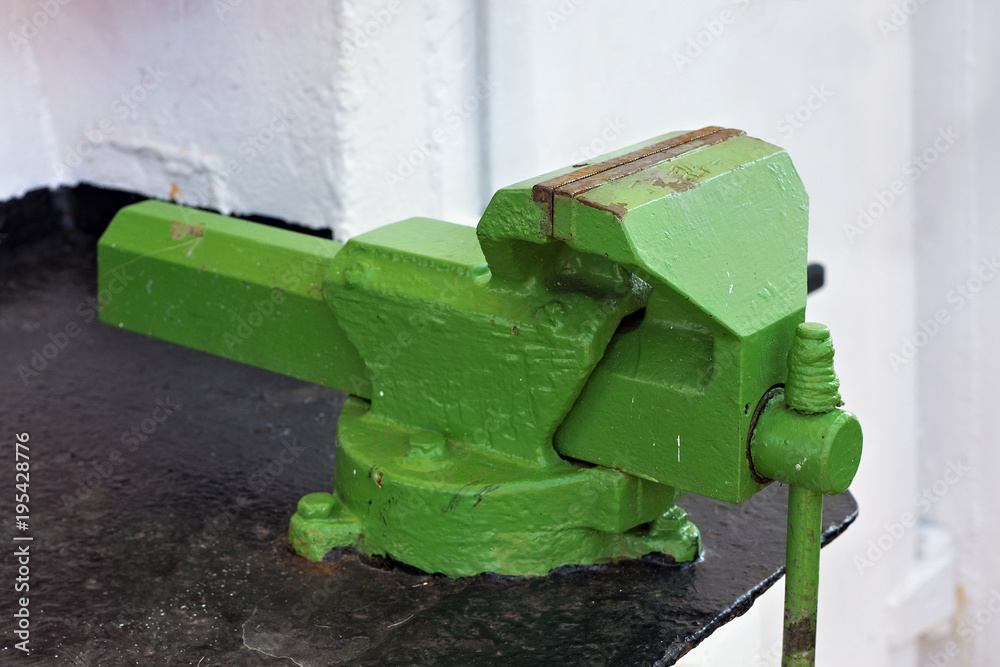 Large old green vise on the steel black table. Large old green vise on the steel black table.