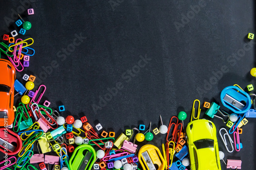 Top view of colorful office equipment with copy space on black chalkboard background. Education concept.