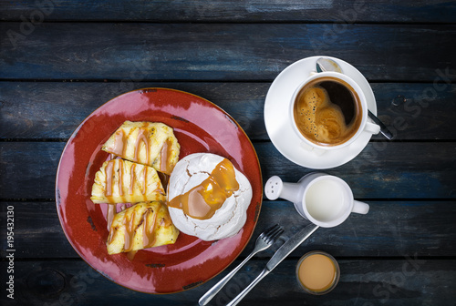 Delicious dessert. Meringue with pineapple and fresh coffee and milk on a colored wooden background. Top view photo