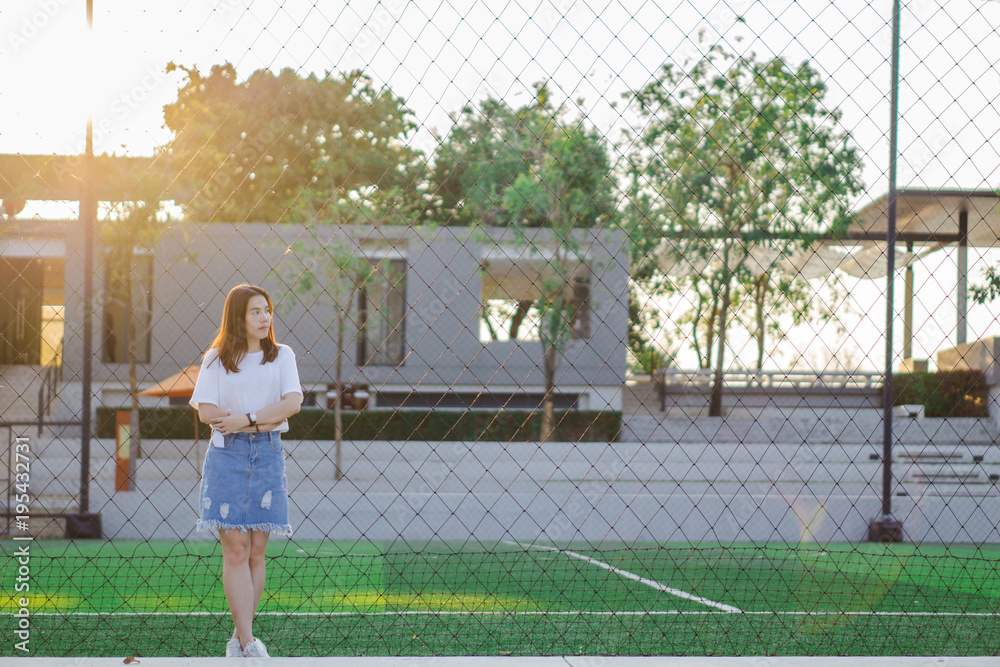 Stress. Protrail stressed sad young woman sticking with  iron net of tennis court, Negative human emotion face expression body language attitude, sunset felling