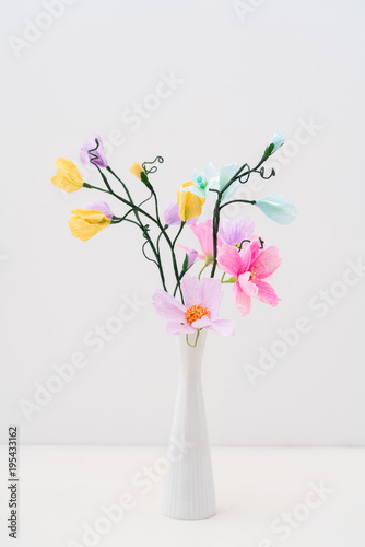 Bouquet of crepe paper cosmos and sweet peas in a vase on white
