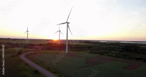 Wind turbines producing renewable energy at sunset - roatating aerial shot photo