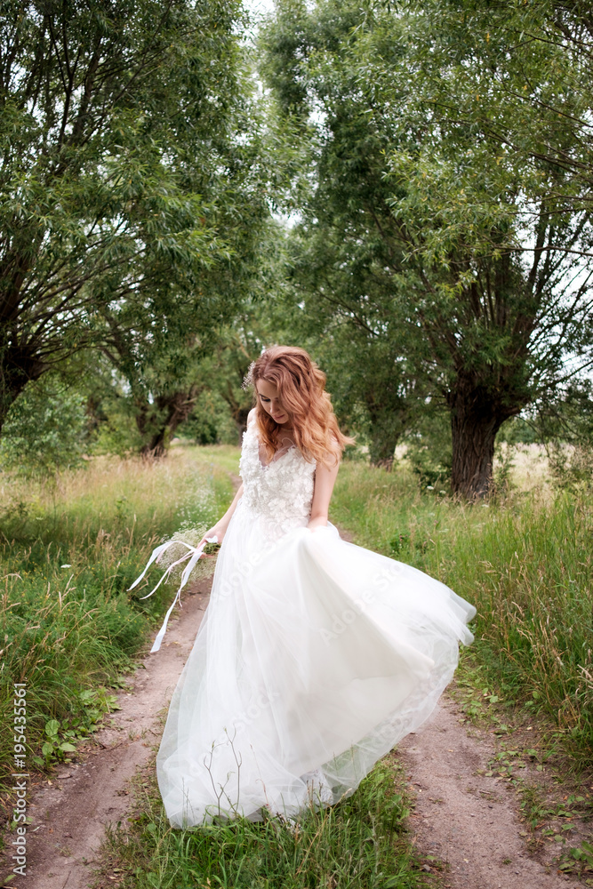 bride in white llight wedding dress with bridal bouquet walking in lane of trees and dancing