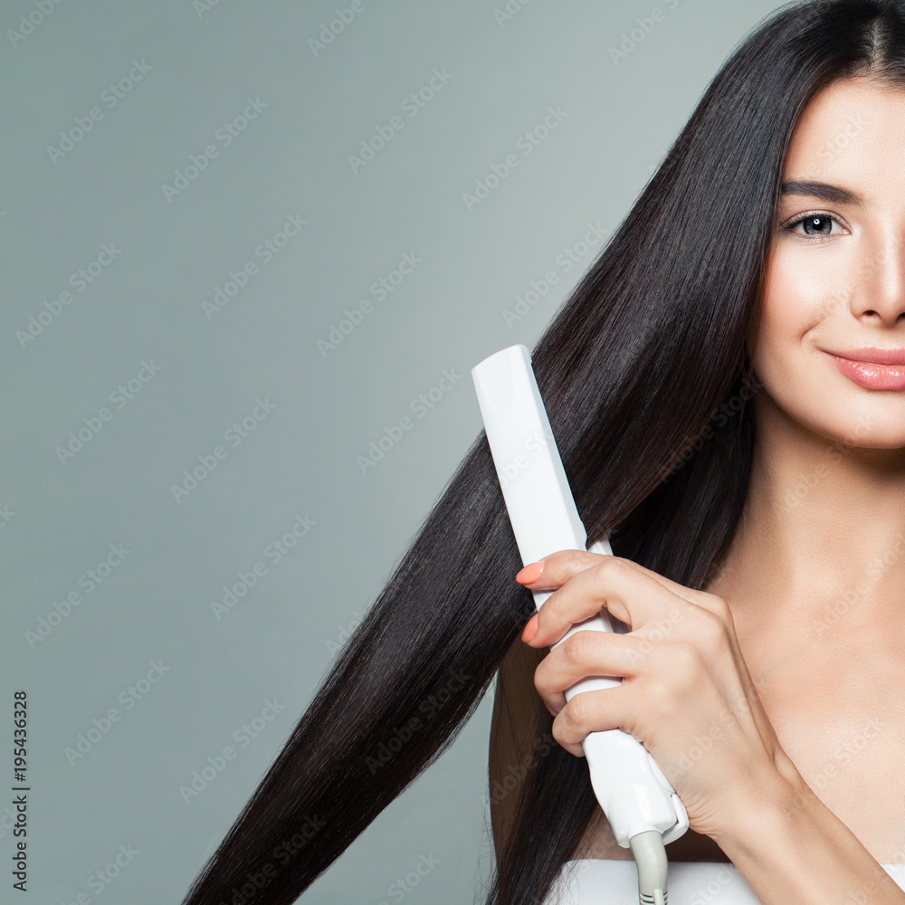 Beautiful Woman with Long Straight Hair Using Hair Straightener. Cute  Smiling Girl Straightening Healthy Brown Hair with Flat Iron on Gray  Background Stock Photo | Adobe Stock