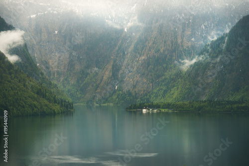 View over misty Lake Konigssee with tiny St Bartholomae church in Berchtesgaden National Park, Bavaria, Germany photo