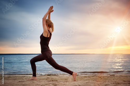 young woman sitting on the beach and practicing yoga