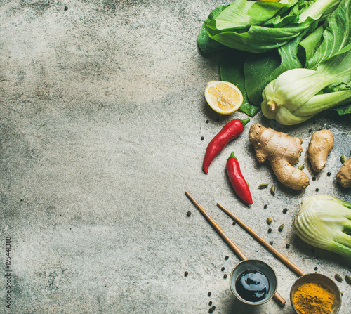 Asian cuisine ingredients over grey background, top view, copy space. Flat-lay of vegetables, spices, sauces for cooking vietnamese, thai or chinese food. Clean eating, vegetarian concept
