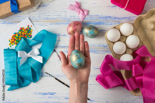 Happy easter. Female hands holding Easter Eggs in the palm of a hand against the background of a wooden table