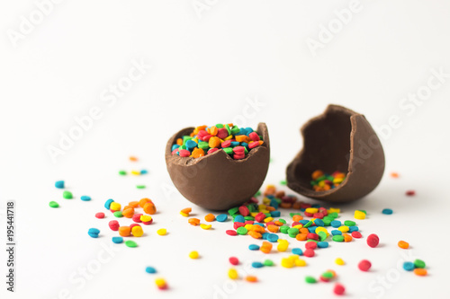 Broken Chocolate Easter egg with multi-colored candy decorations. Copy space