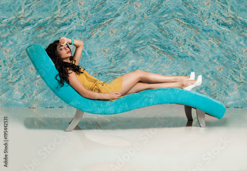 Perfect Young Brunette Woman lying on Sofa against Blue Marble Tiles Wall