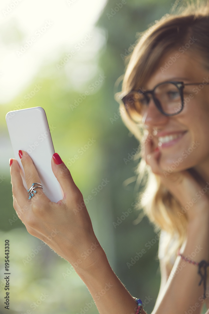 Cute woman doing selfie on smart phone outdoors. Focus on phone. Cute woman doing selfie on smart phone outdoors. Focus on phone.