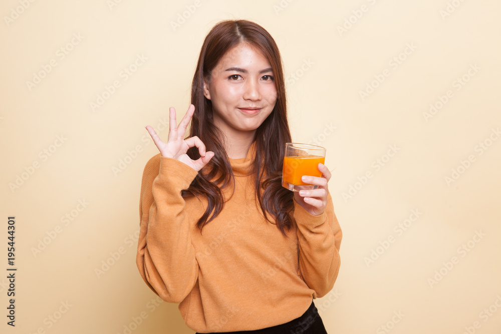 Young Asian woman drink orange juice show OK sign. Young Asian woman drink orange juice show OK sign.
