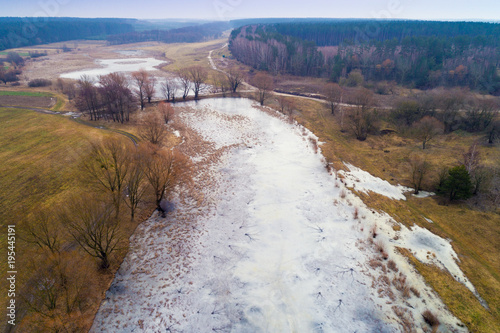 Aerial evening view at countryside with frozen river, fields and forest in early winter photo