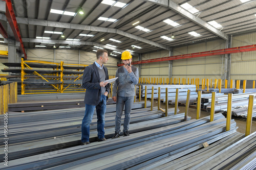 men in warehouse of metal lengths one on walkie talkie © auremar