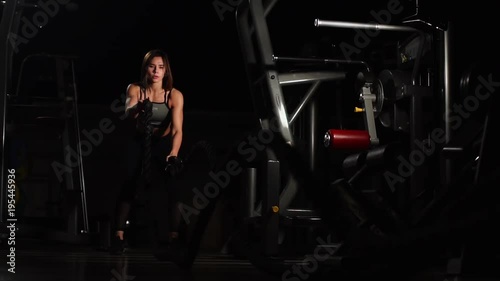 Female athlete working out with heavy ropes at the gym. photo