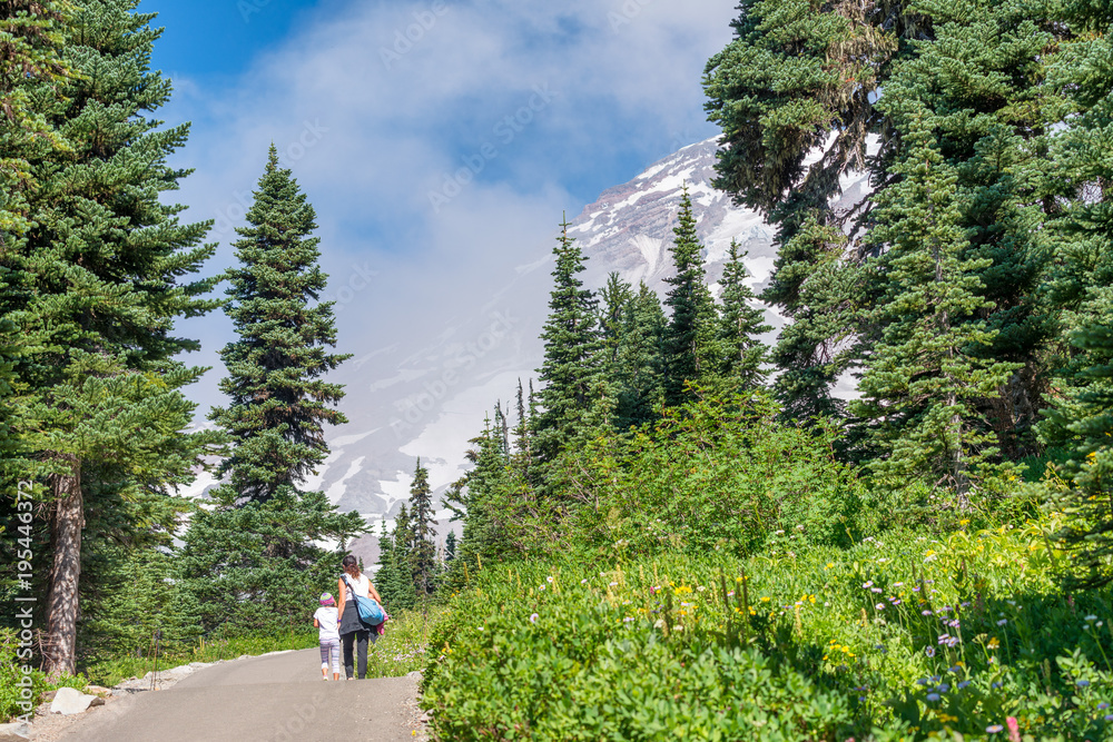 Mother and daughter walking on a beautiful mountain trail in summer season. Holiday concept