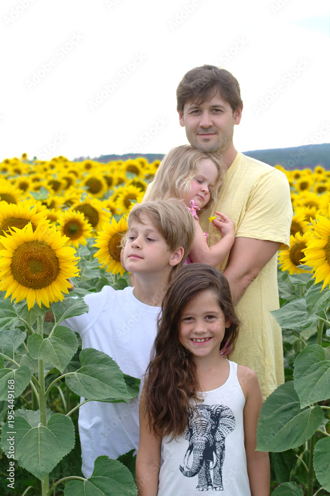 Happy family - father, son and two daughters on a field of sunflowers Happy family - father, son and two daughters on a field of sunflowers