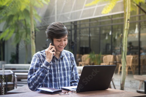 South East Asian Handsome Man In Cafe Working On Laptop And Answering Phone