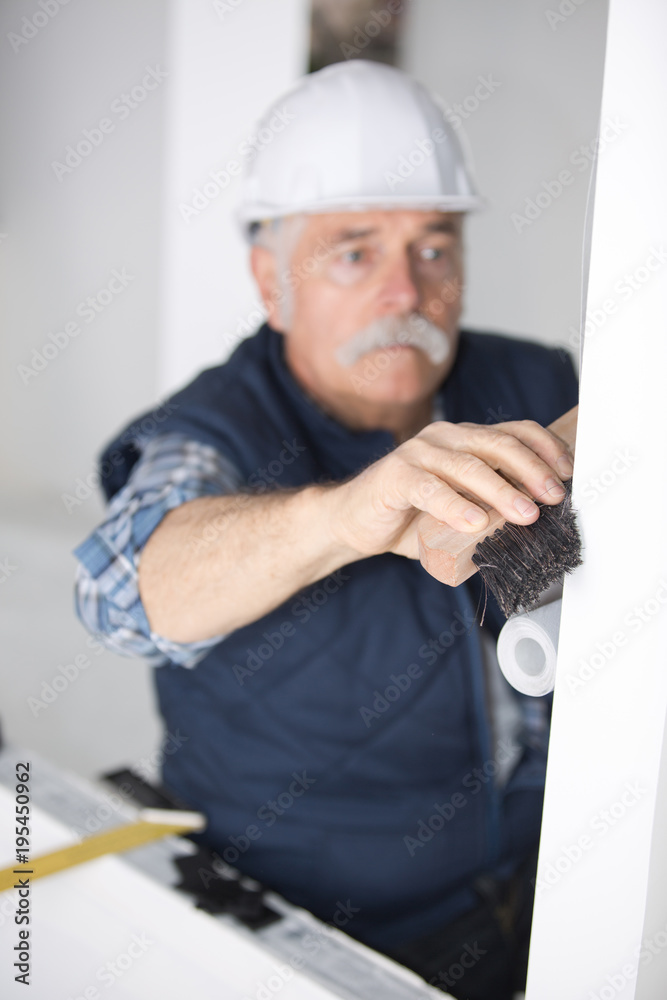 worker cleaning wall surface with a broomstick worker cleaning wall surface with a broomstick