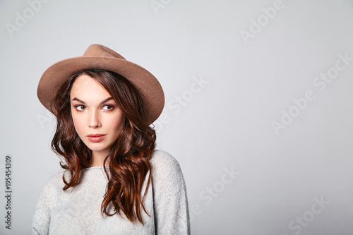 Portrait of young stylish laughing girl model in gray casual summer clothes in brown hat with natural makeup isolated on gray background. Looking at camera