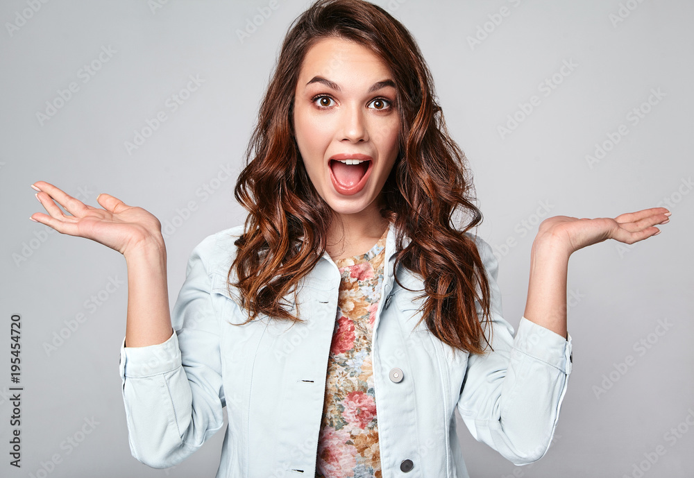 Comparison concept. Young brunette woman in casual summer clothes displaying something on both flat hands for similar choice of product, gray background studio Comparison concept. Young brunette woman in casual summer clothes displaying something on both flat hands for similar choice of product, gray background studio