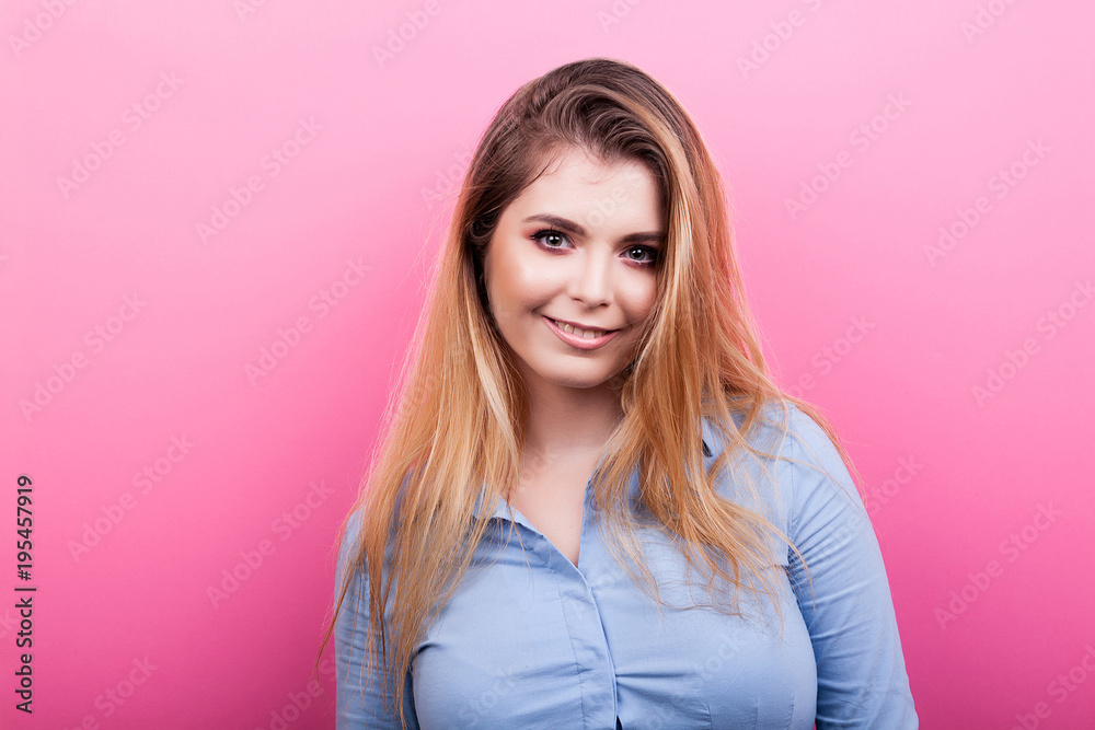 Fototapeta premium Portrait of beautiful blonde woman smiling on pink background