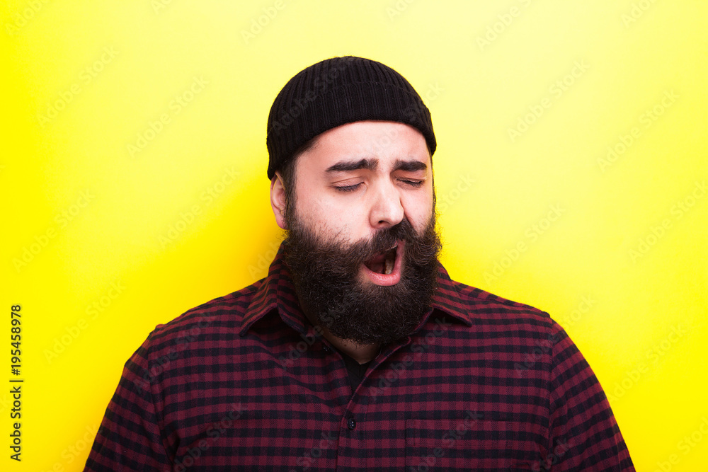 Fototapeta premium Bearded hipster man yawning on yellow background