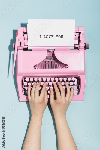 Woman's hands writing "I love you" on a typewriter.