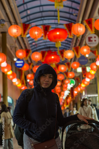 Young woman in arcade in Japan with lanterns overhead.