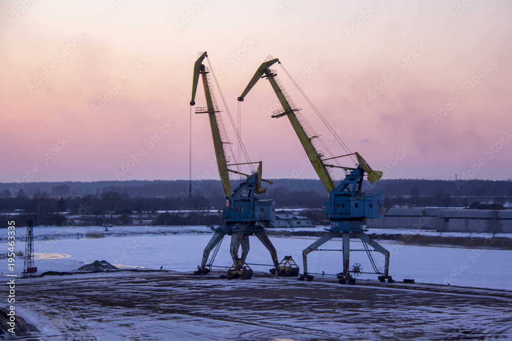 Freight shipping containers and gas oil tanks at the docks. in import export and business logistic. Cargo ship docked at at the port. Cargo cranes by winter evening in the Port Riga, Latvia.