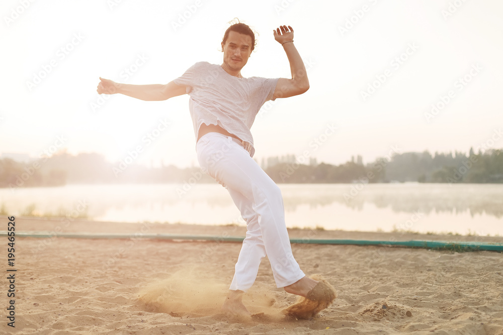 Obraz premium Athletic capoeira performer making movements on the beach
