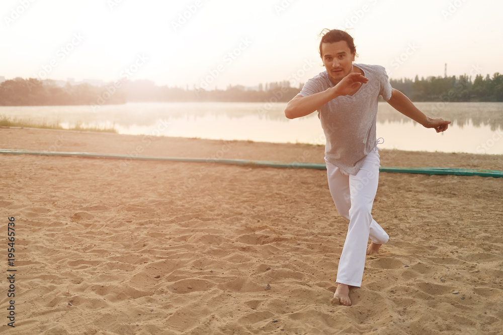Athletic capoeira performer making movements on the beach Athletic capoeira performer making movements on the beach