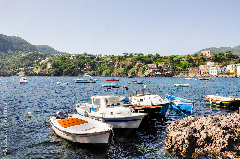 Italian summer holidays in Ischia, blue sea and sky on a Sunny day, beaches and houses on the coast, many white yachts and boats