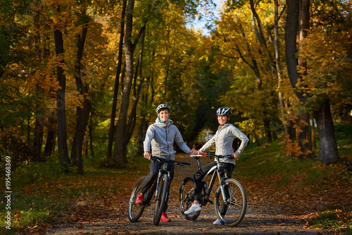 Happy young couple going for a bike ride on an autumn day in the park.