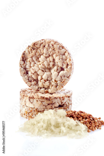 Diet rice cakes pile with buckwheat and rice grains isolated on white background, vertical, selective focus photo