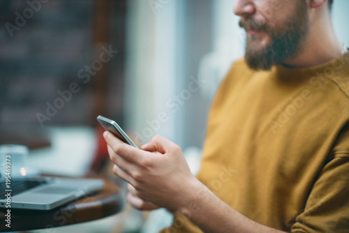 Young man sitting in cafe and using smart phone.