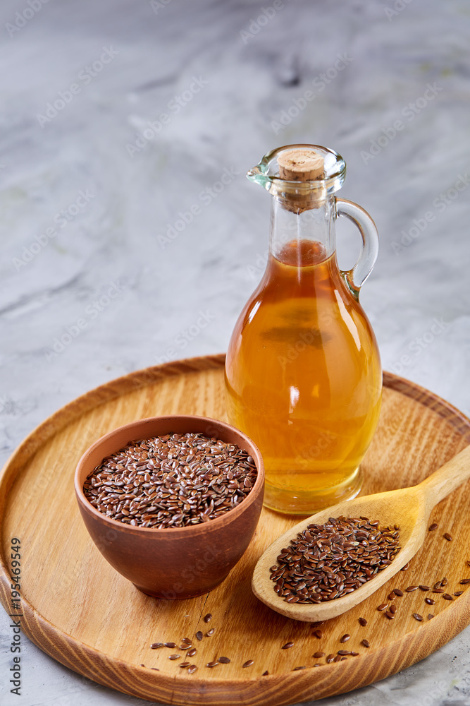 Flax seeds in bowl and flaxseed oil in glass bottle on white background, top view, close-up, selective focus