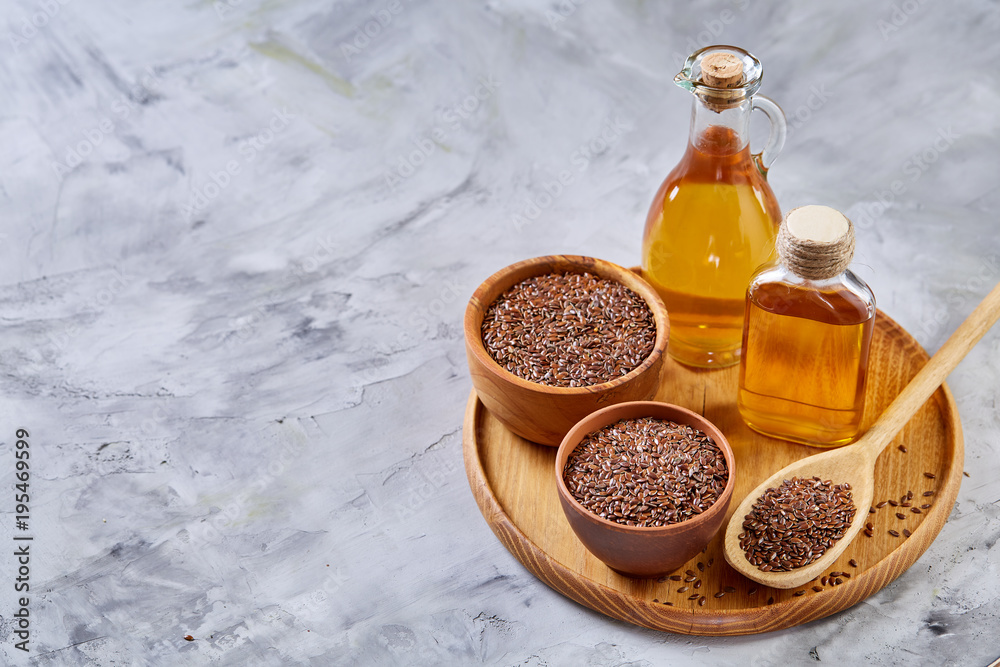 Flax seeds in bowl and flaxseed oil in glass bottle on white background, top view, close-up, selective focus Flax seeds in bowl and flaxseed oil in glass bottle on white background, top view, close-up, selective focus