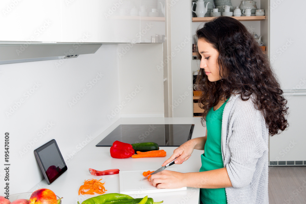 Young woman cooking with the help from a tablet pc