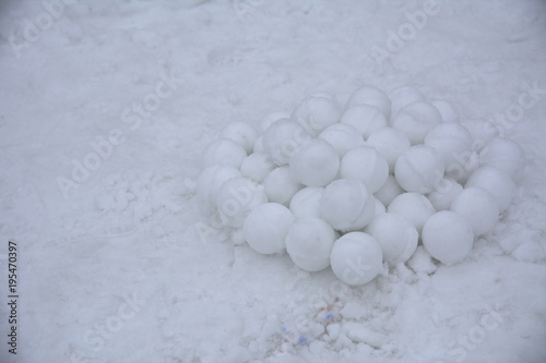A pile of round snowballs for a game of children molded from snow against a background of loose snow. March 2018 Ukraine.