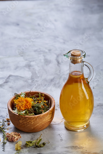 Spa still life with flowers in bowl and oil jars on light textured background, top view, close-up, selective focus