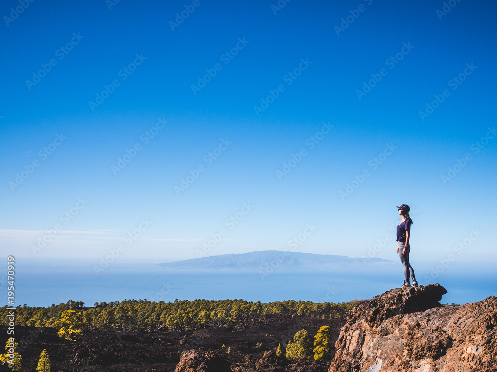 Woman standing on top of a mountain looking far away